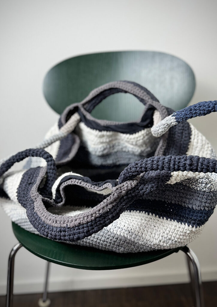 Hand-crocheted bag upcycled from cotton T-shirts in blue, grey and off-white. Opened.