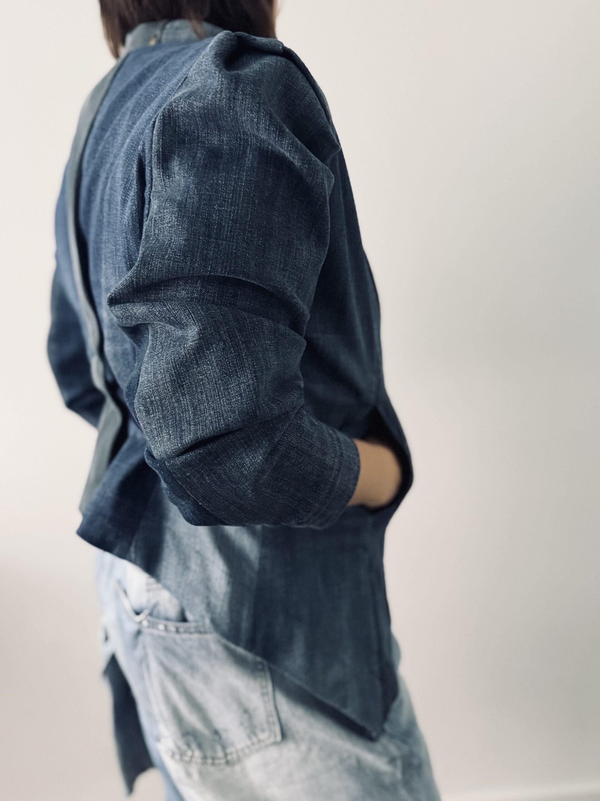 Four-Blues upcycled denim jacket, handcrafted in Zürich. Worn with upcycled jeans Bermuda shorts. Product photo. Right side view.